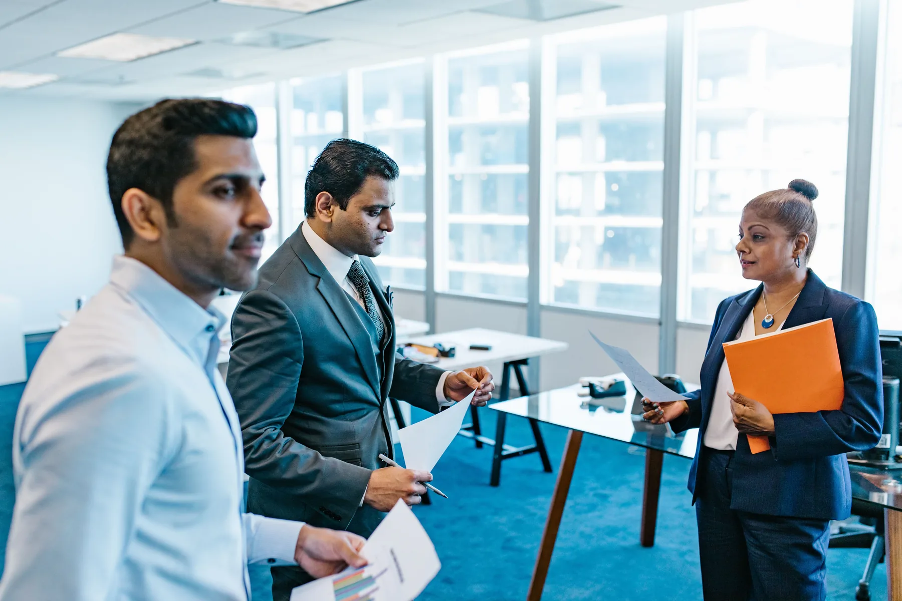 Indian professionals discussing work in a modern office